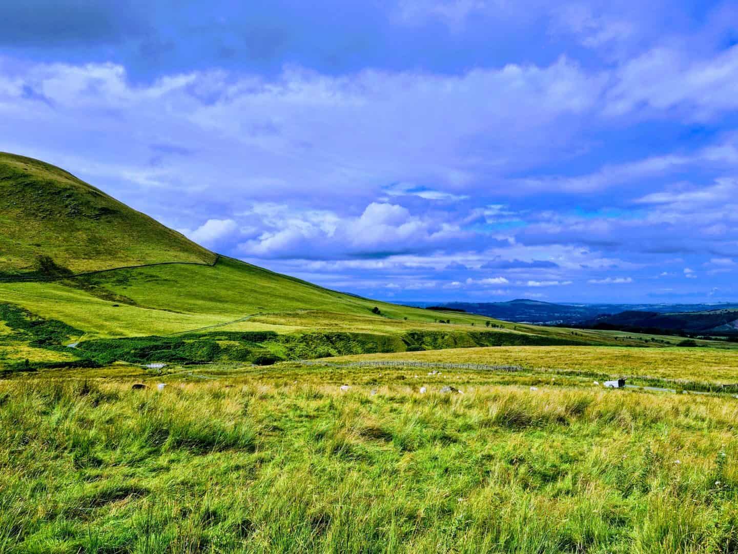 Idyllic view of rolling green hills under a vibrant blue sky, perfect for outdoor and nature themes.